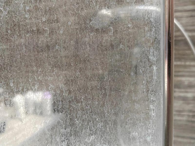 Severely damaged shower glass caused by long-term hard water and limescale buildup in Malta